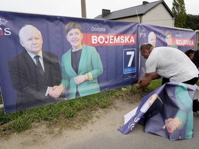A man puts up election banners for a candidate of the ruling conservative Law and Justice party, including an image of the party leader and Poland's de-facto leader Jaroslaw Kaczynski, in Czosnow near Warsaw, on Wednesday, Oct. 11, 2023. The Poles are voting in key parliamentary elections on Sunday that will decide whether Law and Justice wins a third consecutive term, or the pro-European opposition forms the new government. AP Photo/Czarek Sokolowski)