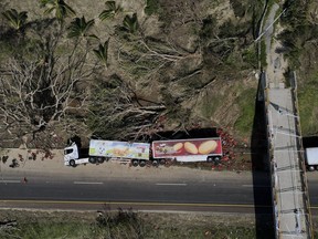 An overturned semi lays on the shoulder of a highway in the aftermath of Hurricane Otis, on the outskirts of Acapulco, Mexico, Friday, Oct. 27, 2023.