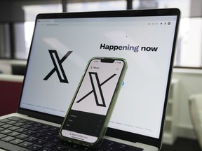 The opening page of X is displayed on a computer and phone in Sydney, Monday, Oct. 16, 2023. Australia's online safety watchdog has fined X, formerly known as Twitter, $385,000 for failing to explain how it tackles child sexual exploitation on the social media platform.