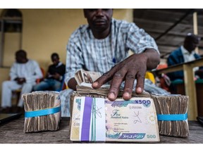 A currency dealer handles bundles of naira banknotes for exchange on the 'black market' in Lagos, Nigeria.