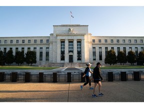 Joggers pass the Marriner S. Eccles Federal Reserve building in Washington, DC.