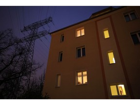 A high voltage electricity transmission tower near a partially lit apartment block in a residential district of Berlin, Germany, on Monday, Nov. 21, 2022. The German government plans to collect windfall profits from electricity companies despite legal uncertainties about the proposal, according to a government paper seen by Bloomberg.