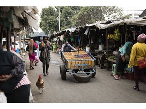 A worker pushes a cart past market shacks in Nairobi, Kenya, on Tuesday, July 25, 2023. The leader of Kenya's main opposition coalition Raila Odinga said he's ready to hold talks with the government even as he vowed to continue with demonstrations to demand tax cuts and an audit of last year's elections that brought President William Ruto to power. Photographer: Patrick Meinhardt/Bloomberg