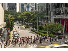 Pedestrians cross a road on Orchard Road in Singapore, on Monday, Nov. 20, 2023. Singapore's gross domestic product figures for the third quarter are scheduled to be released on Nov. 22.