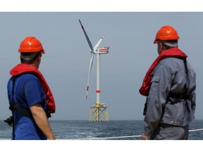Workers look out at an offshore wind farm.