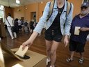 A man, right, waits as a woman drops her ballot into a box a polling place in Redfern as Australians cast their final votes in Sydney, Saturday, Oct. 14, 2023, in their first referendum in a generation that aims to tackle Indigenous disadvantage by enshrining in the constitution a new advocacy committee. 
Voters soundly rejected the proposal.