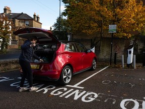 A person prepares to charge an electric vehicle in London, U.K.