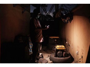 A man using his phone as a source of light trying to switch oon his generator set in Lagos, on 30 Sept, 2023