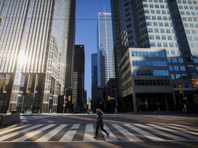 A woman crosses the street in the financial district in Toronto.