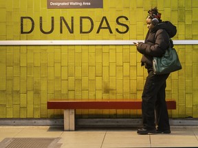 A woman uses her phone while waiting for the TTC Subway at Dundas Street and Yonge Street in Toronto.