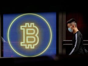 A commuter passes a digital display of cryptocurrency Bitcoin in central district in Hong Kong, China.