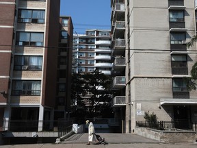 A pedestrian passes in front of apartment buildings in the Parkdale neighbourhood of Toronto.