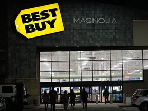 FILE - Shoppers are silhouetted as they walk toward a Best Buy store after doors opened at 5 a.m., Nov. 26, 2021, in Lone Tree, Colo. Best Buy Co. posted stronger-than-expected profits, Tuesday, Nov. 21, 2023, but reported a drop in revenue for the fiscal third quarter as shoppers continue to pull back on buying gadgets in an uncertain economy.