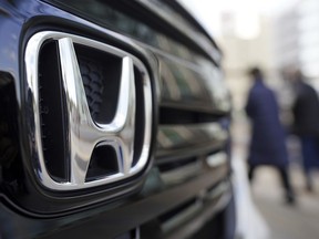 FILE - People walk near the logo of Honda Motor Company at a showroom Tuesday, Feb. 8, 2022, in Tokyo. Honda is recalling several hundred thousand 2023-2024 Accord and HR-V vehicles, Saturday, Nov. 25, 2023, due to a missing piece in the front seat belt pretensioners, which could increase injury risks during a crash.