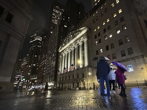 File - People huddle outside the New York Stock Exchange on Tuesday, Nov. 21, 2023 in New York.
