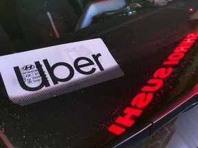 File - An Uber sign is displayed inside a car in Glenview, Ill., on Dec. 17, 2022. Ride-hailing companies Uber and Lyft will pay a combined $328 million to settle wage theft claims in New York, Attorney General Letitia James announced Thursday.