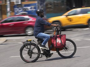 FILE - A delivery worker rides a motorized bicycle, July 25, 2023, in New York. On Monday, Nov. 13, New York City officials said that retailers and food delivery companies must do more to halt the proliferation of unsafe e-bike and e-scooter batteries after a fire blamed on an electric scooter's lithium ion battery killed three people over the weekend.