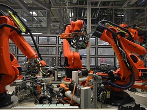 Robot arms assembling electric vehicle engines at a factory in Hungary.