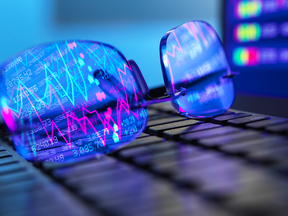 Stock tickers reflected in the lenses of a pair of glasses.