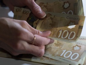 An Interac survey shows 40 per cent of Canadians are concerned that they could fall victim to a financial scam. Canadian $100 bills are counted in Toronto, Feb. 2, 2016.