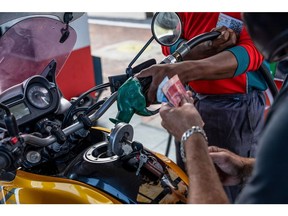A worker refuels a motorcycle at a gas station in Cape Town. Photographer: Dwayne Senior/Bloomberg