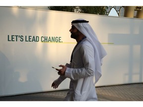 An attendee passes a sign reading 'Let's Lead Change' in the Blue Zone on day two of the COP28 climate conference at Expo City in Dubai, United Arab Emirates, on Friday, Dec. 1, 2023. More than 70,000 politicians, diplomats, campaigners, financiers and business leaders will fly to Dubai to talk about arresting the world's slide toward environmental catastrophe. Photographer: Annie Sakkab/Bloomberg