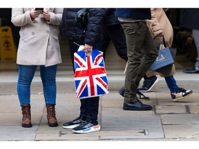 A shopper with a British Union flag branded bag on Piccadilly in London, UK, on Monday, Dec. 18, 2023. Photographer: Chris Ratcliffe/Bloomberg