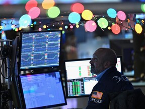 A trader works on the floor of the New York Stock Exchange with Christmas lights in the background.