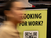 A woman walks past a jobs sign