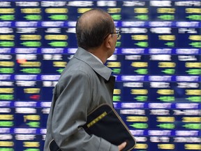 A pedestrian looks at a quotation board flashing the Nikkei key index from the Tokyo Stock Exchange in Tokyo.