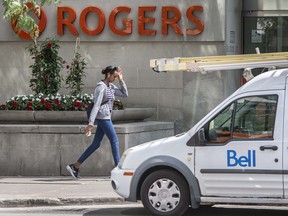 A pedestrian walks past the Rogers Communications Inc. moniker.