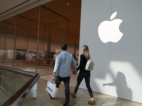 File - People walk by an Apple store Oct. 20, 2023, in Denver. Apple is now requiring that U.S. law enforcement agencies obtain a court order for information on its customers' push notifications -- the alerts iPhone apps send users that can reveal a lot about their online activity.