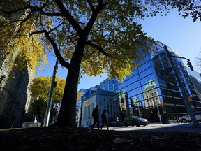 People make their way past the Bank of Canada building on Wellington Street in Ottawa on Monday, Oct. 23, 2023. The Bank of Canada will make its last scheduled interest rate announcement of the year on Wednesday.