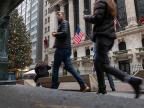 People walk past the New York Stock Exchange on Dec. 26. Investors are full of optimism for 2024 as the S&P 500 index sits within striking distance of its first all-time high in nearly two years.