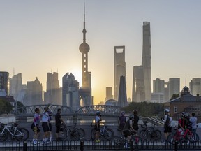 FILE - In this photo released by Xinhua News Agency, cyclists, some take selfie as they take rest against the sunrise skylines in Pudong, China's financial and commercial hub, in Shanghai, China on Friday, Nov. 3, 2023. Credit rating agency Moody's cut its outlook for Chinese sovereign bonds to negative on Tuesday, Dec. 5, 2023, citing risks from a slowing economy and a crisis in its property sector.
