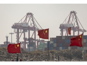 Shipping containers seen beyond Chinese flags on fishing boats near the Yangshan Deepwater Port in Shanghai, China, on Wednesday, Dec. 6, 2023. China's trade figures are scheduled for release on Dec 7. Photographer: Qilai Shen/Bloomberg