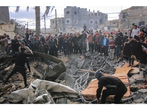 Palestinians search the rubble of buildings destroyed by an Israeli airstrike in Khan Younis, southern Gaza, on Friday, Jan. 12, 2024.