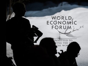 Participants are silhouetted in front of signage as they wait prior to a session at the World Economic Forum (WEF) meeting in Davos.