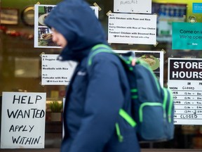 A pedestrian walks past a 'Help Wanted' sign in downtown Toronto. Cutting off the arrival of temporary residents to Canada could hurt the economy, Desjardins warns.