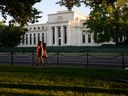 Pedestrians walk past the United States Federal Reserve in Washington, D.C.