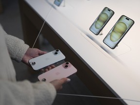 A shopper compares two iPhone 15 models at an Apple Inc. store in Los Angeles, 2023.