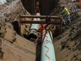 Workers lay pipe during construction of the Trans Mountain pipeline expansion on farmland in Abbotsford, B.C., 2023.