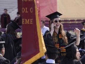 File - A graduating Boston College student speaks on a phone during commencement ceremonies on May 22, 2023, in Boston. The Free Application for Federal Student Aid, or FAFSA, has been available on and off for a few days now. While many have been able to take advantage of the new shorter application, many others have struggled to even open the application.
