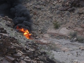 FILE - A survivor, lower right, walks away from the scene of a deadly tour helicopter crash along the jagged rocks of the Grand Canyon, Feb. 10, 2018, in Arizona. On Friday, Jan. 5, 2024, a Nevada judge approved a $100 million cash settlement to the parents of a British tourist who was among five killed -- including his newlywed wife-- when the helicopter crashed and burst into flames in the Grand Canyon in 2018.