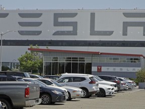 FILE - A man walks in the Tesla plant parking lot, May 11, 2020, in Fremont, Calif. Factory workers at Tesla have been told to expect pay raises in 2024, a move that comes as the United Auto Workers union tries to organize the electric vehicle maker's U.S. plants. The UAW said Thursday, Jan. 11, 2024, that Tesla workers have told the union about company statements on the raises, which did not give details about the size of the increases.
