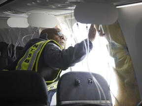 In this photo released by the National Transportation Safety Board, NTSB Investigator-in-Charge John Lovell examines the fuselage plug area of Alaska Airlines Flight 1282 on Sunday, Jan. 7, 2024, in Portland, Ore. A panel used to plug an area reserved for an exit door on the Boeing 737 Max 9 jetliner blew out Friday night shortly after the flight took off from Portland, forcing the plane to return to Portland International Airport. (National Transportation Safety Board via AP)
