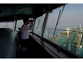 A crew member uses binoculars on the bridge of the oil tanker 'Devon' as it prepares to transfer crude oil from Kharg Island oil terminal to India, in the Persian Gulf, Iran, on Friday, March 23, 2018. Geopolitical risk is creeping back into the crude oil market. Photographer: Ali Mohammadi/Bloomberg
