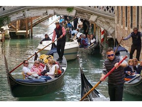 Gondoliers transport tourists in gondolas along a canal in Venice in April 2023.  Photographer: Andrea Merola/Bloomberg