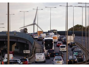 Vehicles travel along the A13 arterial road against the backdrop of a wind turbine in London, UK, on Monday, Nov. 13, 2023. A levy on drivers of older cars with dirtier engines has pushed many of them off London's roads, reducing pollution that's been blamed for thousands of deaths in the capital each year. Photographer: Chris Ratcliffe/Bloomberg