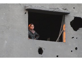 A Palestinian woman looks out from the window of a damaged building following an Israeli airstrike in the Nuseirat refugee camp, central Gaza, on Wednesday, Feb. 28, 2024. Discussions on Israel agreeing to pause the war in Gaza in exchange for the release of more hostages held by Hamas have intensified in recent days.